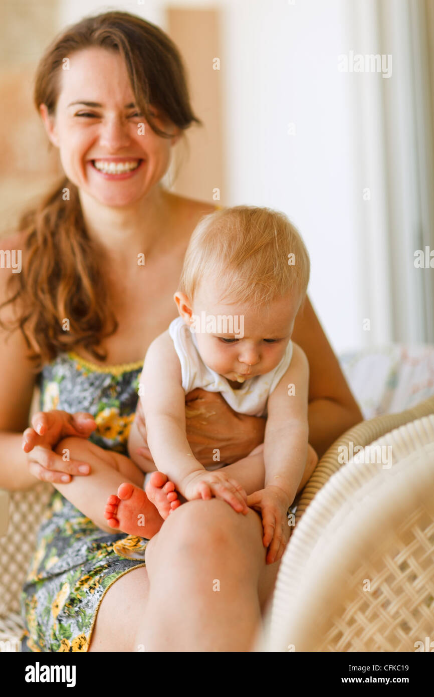 Mutter mit Baby-sitting auf Knien zu lachen Stockfoto