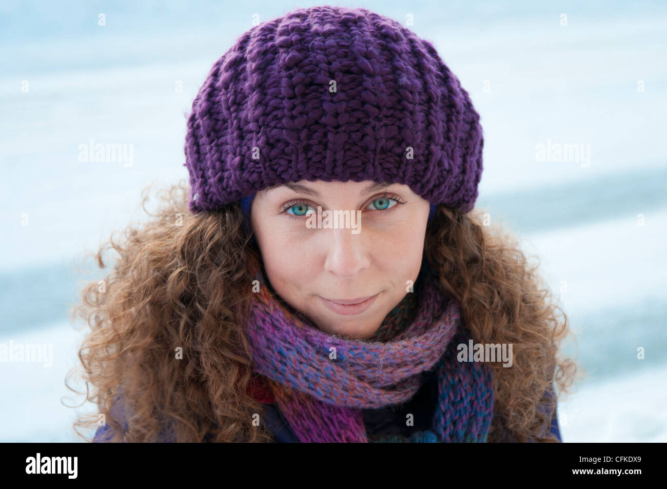 Mädchen im Schnee schaut direkt in die Kamera mit einem lila Hut und Schal in Tromsø, Norwegen Stockfoto