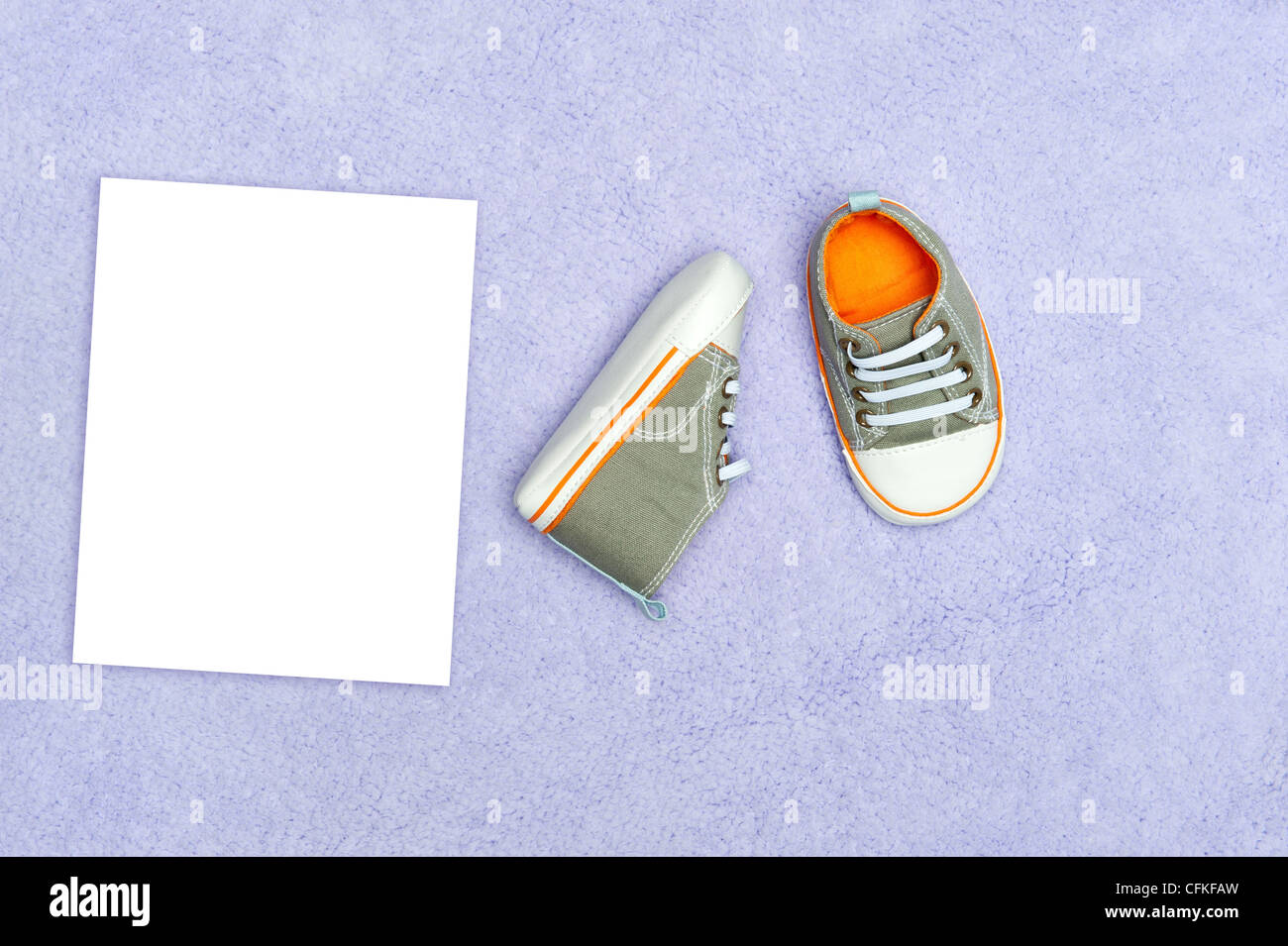Ein paar neue Baby jungen Tennis Schuhe auf eine lila Decke mit leeren weißen Karte für die Platzierung der Kopie Stockfoto