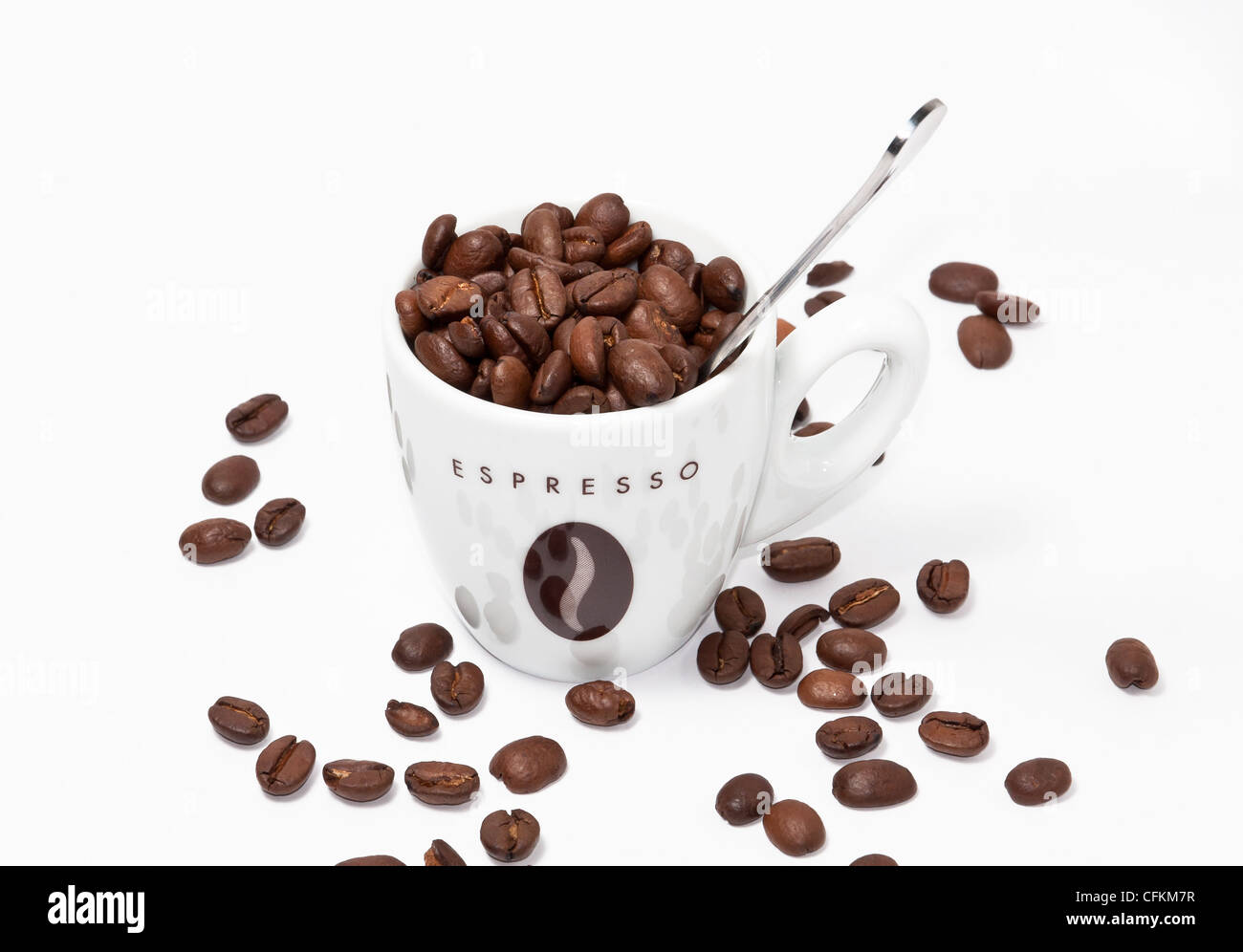 Espressotasse voll Kaffee Bohnen mit einem Löffel auf weißem Hintergrund. Stockfoto