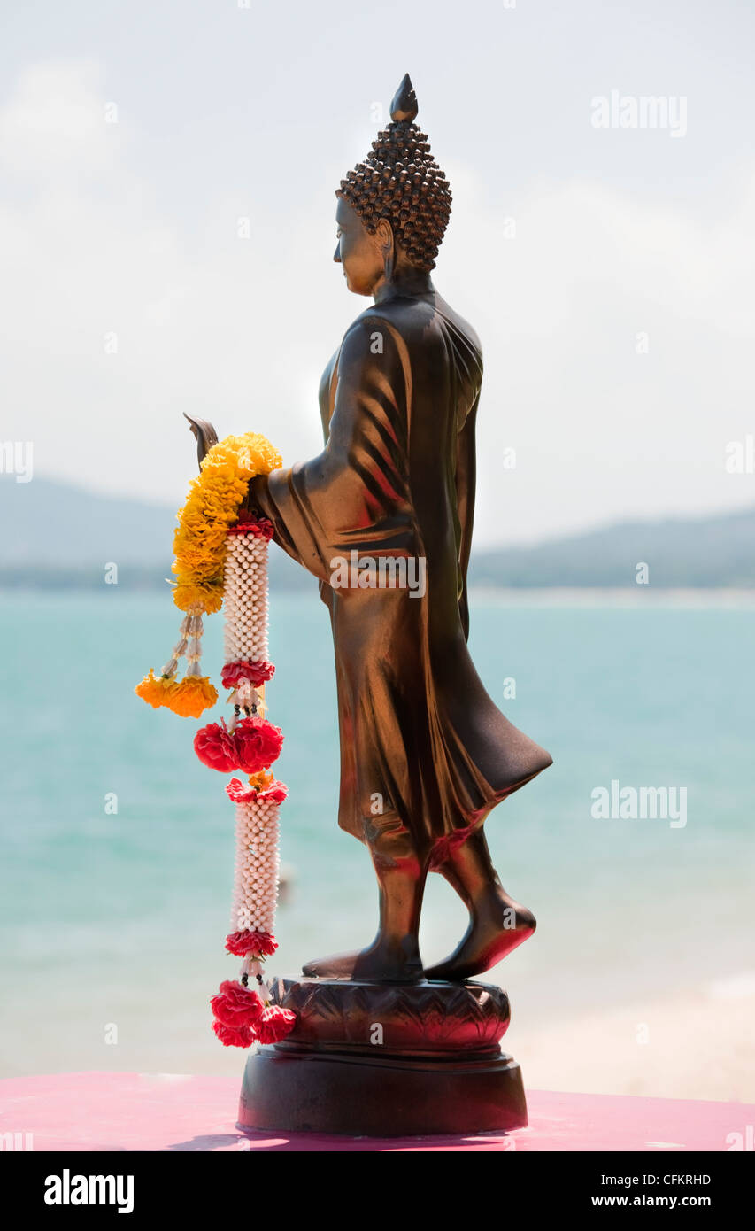 Eine religiöse Statue mit bunten Girlanden mit Blick auf einen Strand am Maenam Beach Koh Samui in Südthailand Stockfoto