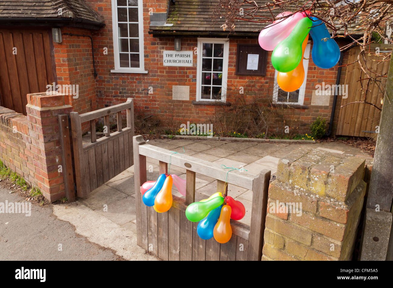 Hängenden Trauben von Party Luftballons außerhalb Seher grünes Dorf Kirche Pfarrsaal. Stockfoto