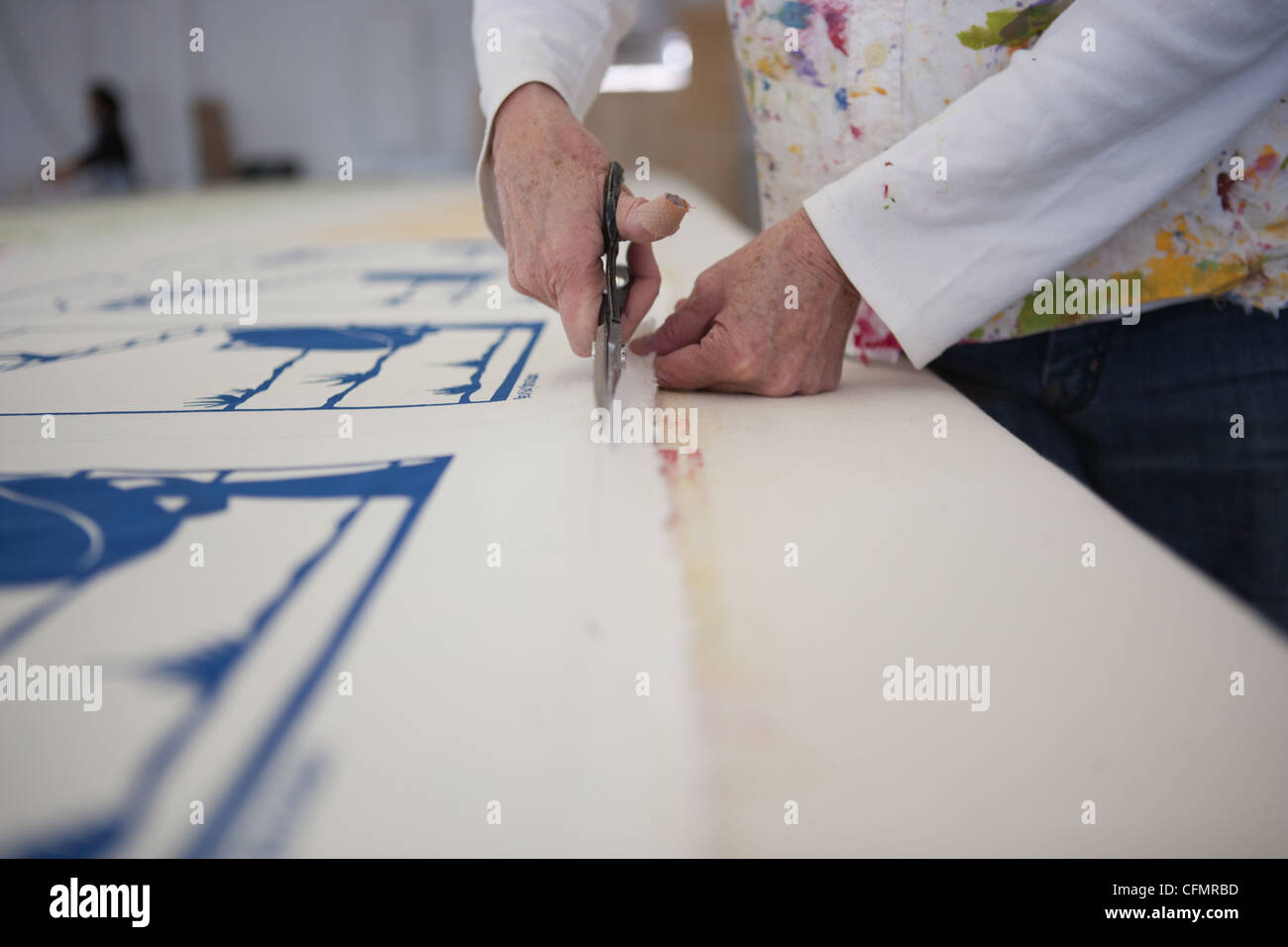 Eine Frau Schneiden Stoff auf einem großen Tisch mit einer Schere. Stockfoto