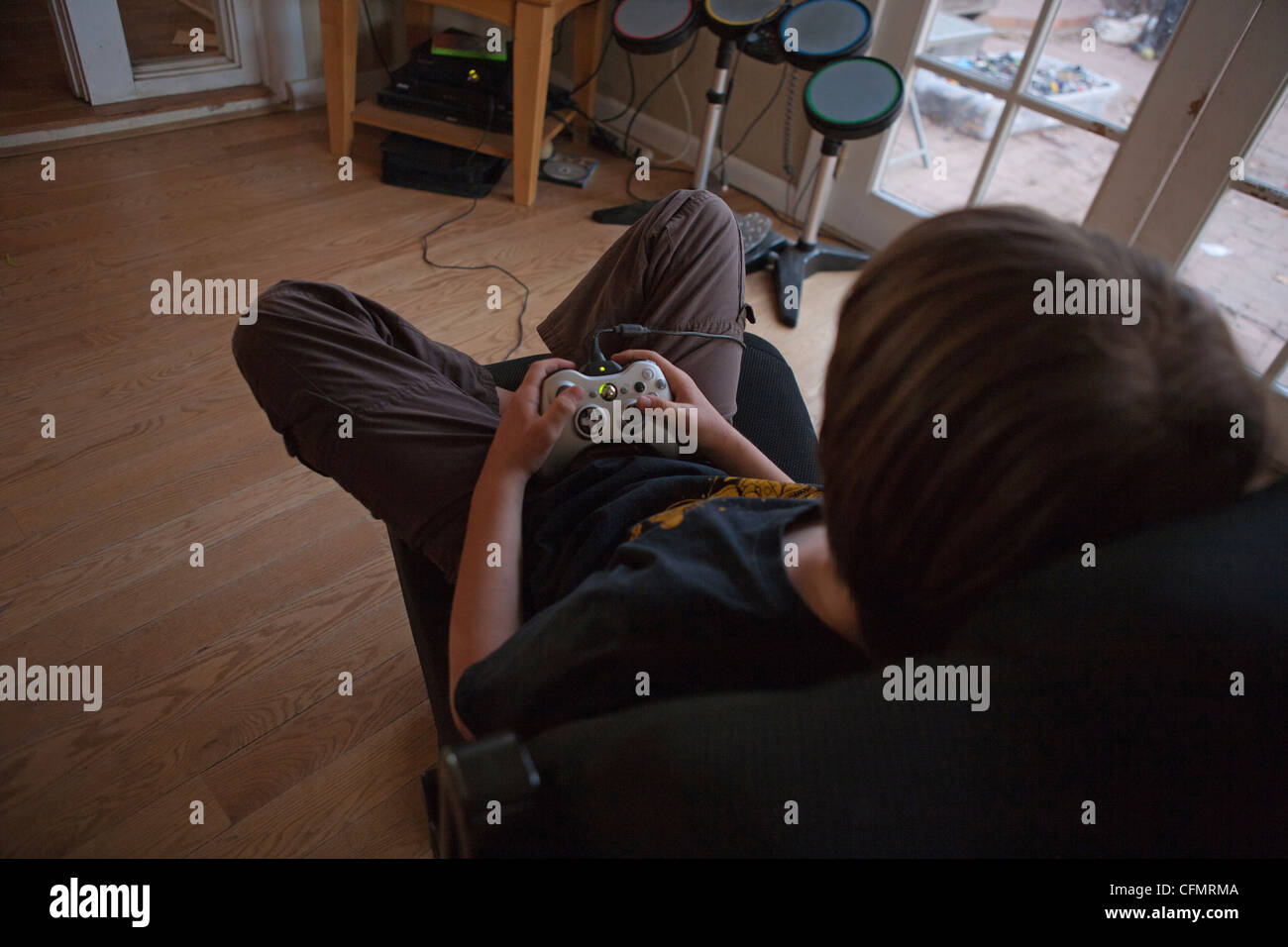 Neun Jahre alter Junge sitzt auf einem Stuhl eine Xbox 360 Spiel zu spielen in Wohnzimmer zu Hause. Stockfoto
