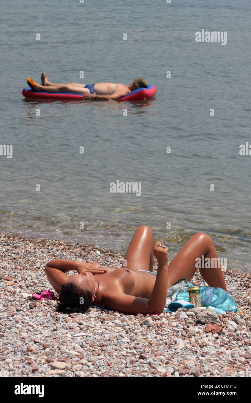 Frau, Sonnenbaden am Strand nackt, während ein Mann auf der Luftmatratze treiben. Budva. Montenegro Stockfoto