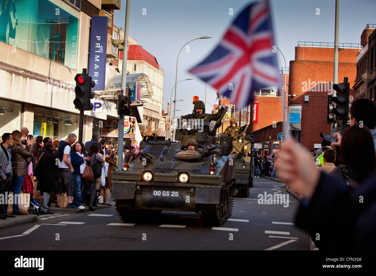 Truppen in gepanzerten Fahrzeugen vorbeifahren High Street Läden während einer Parade Royal Yeomanry, winken Zuschauern Union Jack-Flaggen Stockfoto