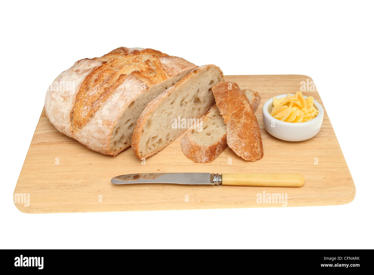 Rustikales Brot mit geschnittenen Scheiben, Butter und ein Messer auf einem Brot-Brett isoliert gegen weiß Stockfoto