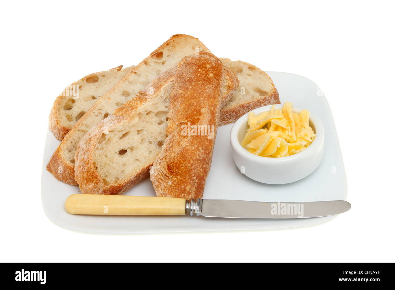 Scheiben Bauernbrot auf einem Teller mit Butter und ein Messer isoliert gegen weiß Stockfoto