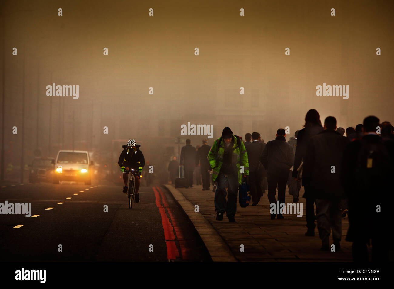 Ein maskierter Radfahrer und Pendler Reise quer durch London Bridge an einem smoggy Morgen Stockfoto