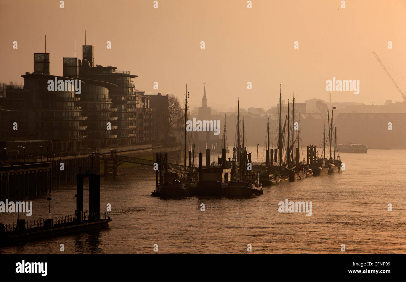 Entlang dem Nordufer der Themse von der Tower Bridge sieht die festgemachten Boote und Fluss-Apartments entstehen durch Londons Nebel Stockfoto