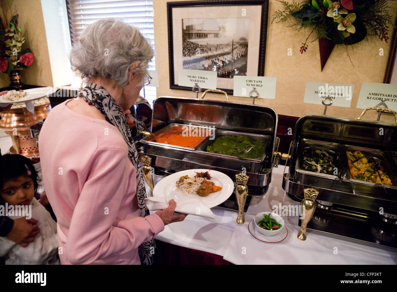 Eine ältere Dame, die sich selbst Speisen im Tamasha indischen Restaurant, Bromley, Kent UK Stockfoto