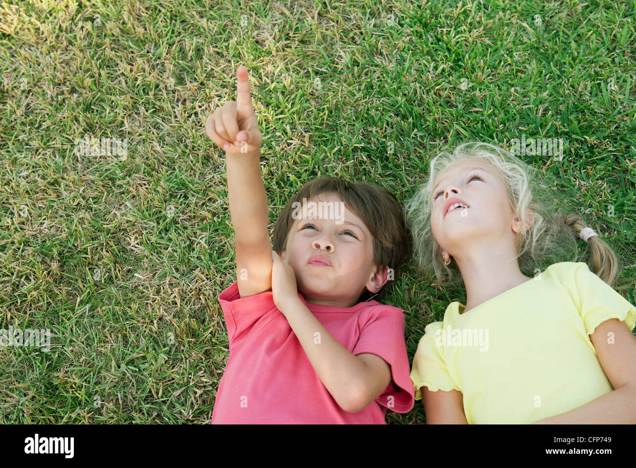 Jungen und Mädchen auf dem Rasen liegen, nachschlagen und verweisen Stockfoto