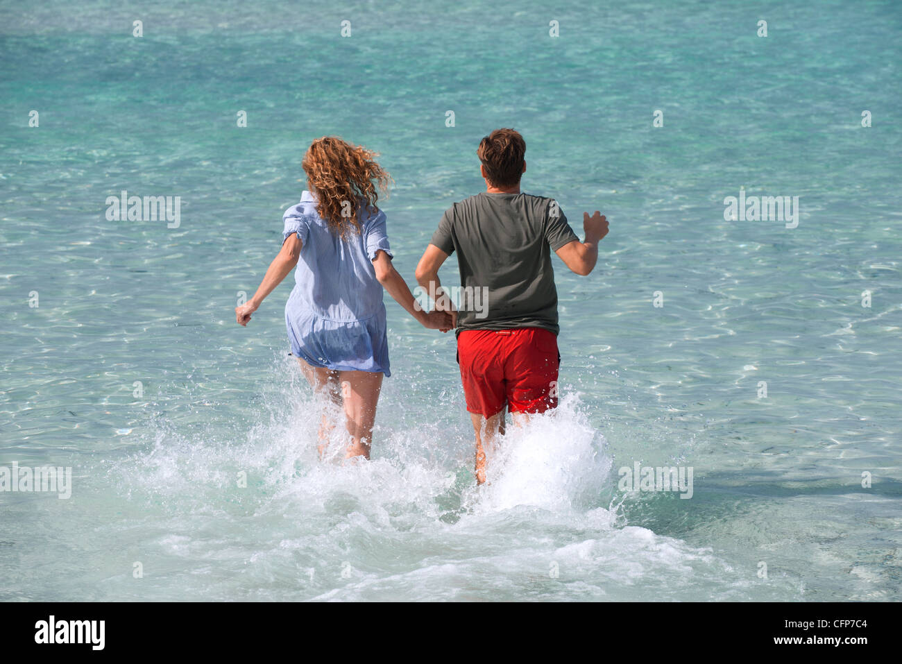 Paar laufen ins Wasser halten Händchen, Rückansicht Stockfoto