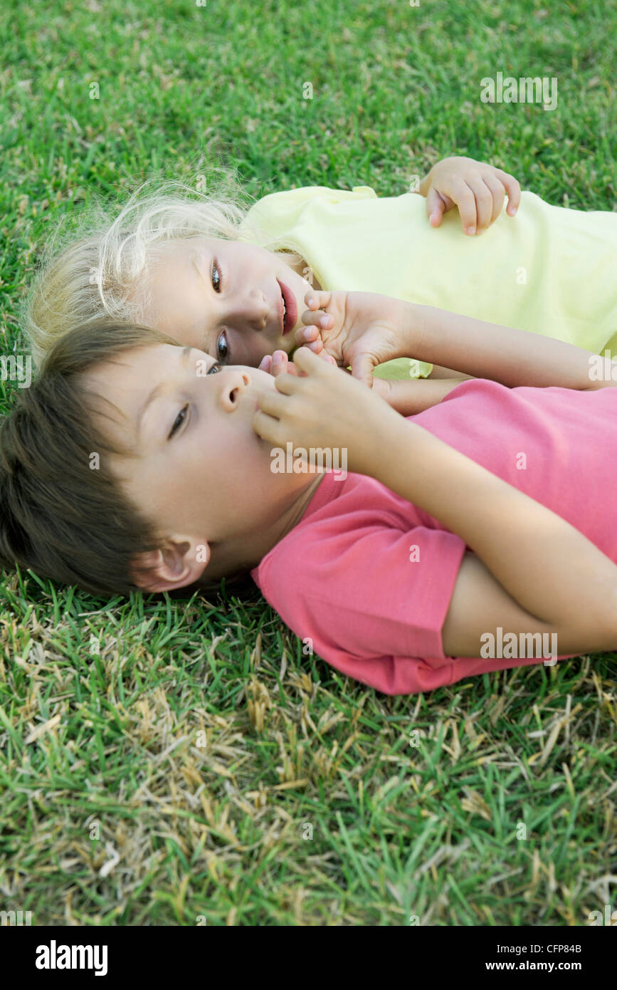 Junge Freunde liegen zusammen auf dem Rasen Stockfoto
