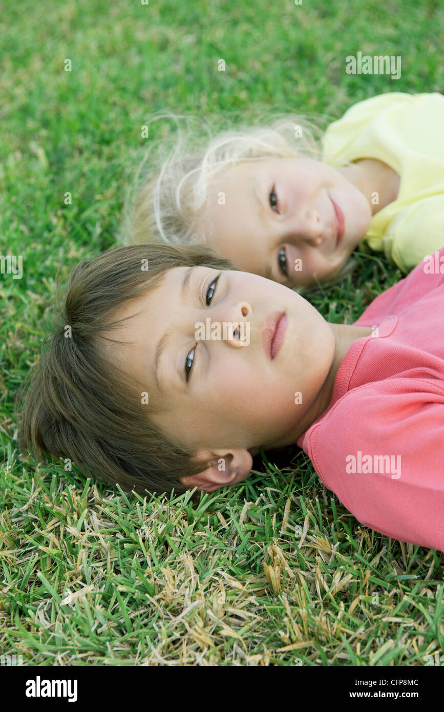 Jungen und Mädchen liegen auf dem Rasen, Porträt Stockfoto