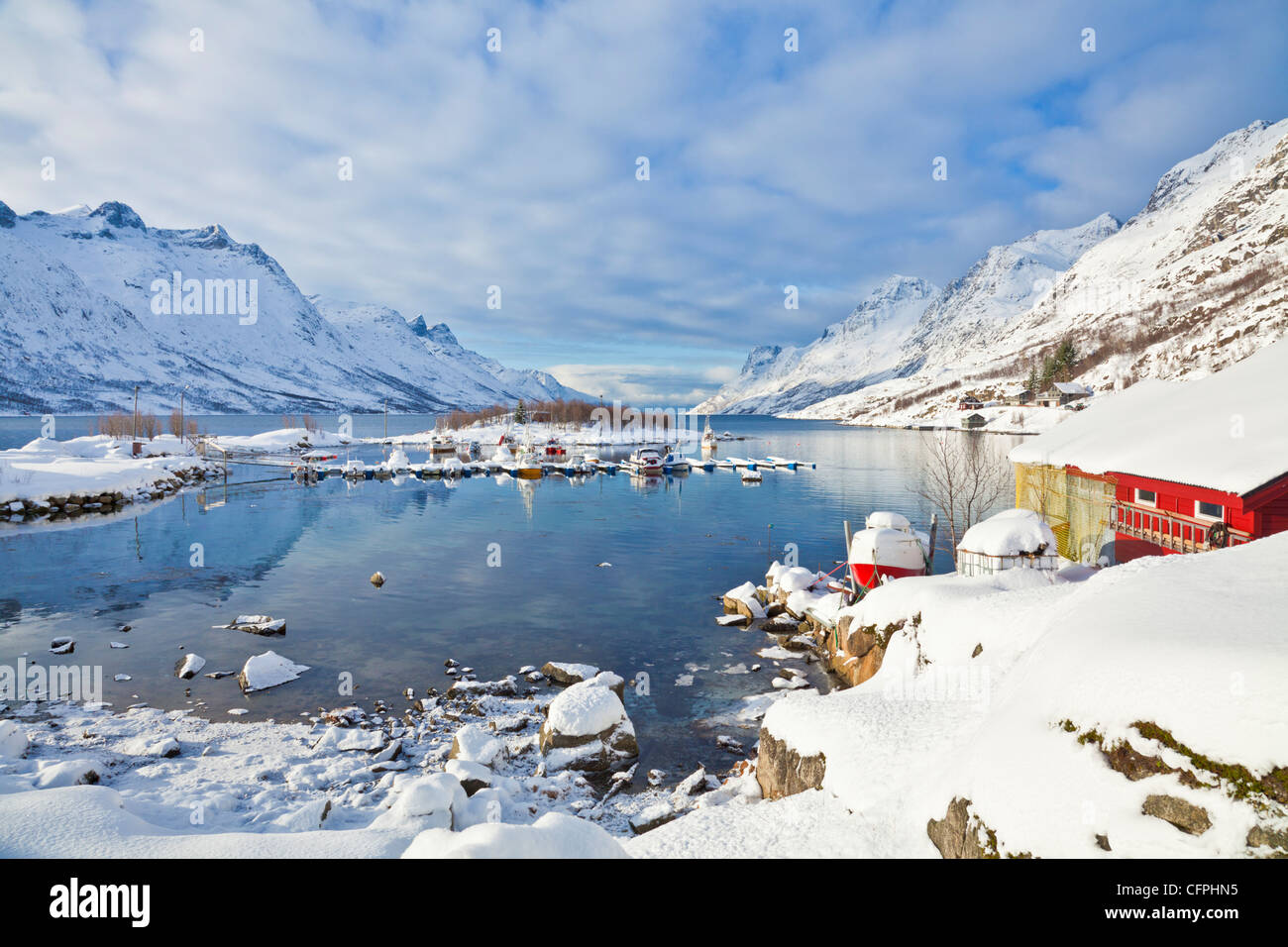 Schneebedeckte Berge, Bootshaus und Liegeplätzen im norwegischen Fjord Dorf von Ersfjord, Kvaloya Insel, Troms, Norwegen, Europa Stockfoto
