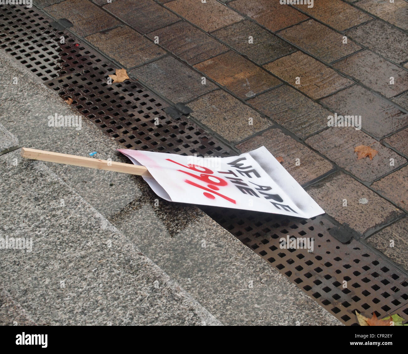 Wir sind die 99 % Plakat auf nassen Schritte nach einer Demonstration gegen Kürzungen der Regierung verworfen. Stockfoto