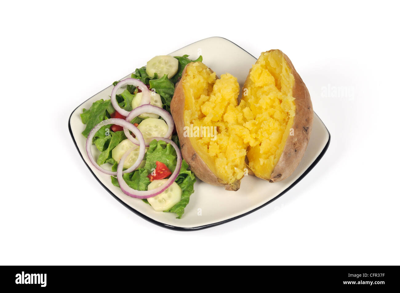 Gebackene Süßkartoffel mit zerlassener Butter mit grünem Garten Salat auf einem Teller auf weißem Hintergrund ausschneiden Stockfoto
