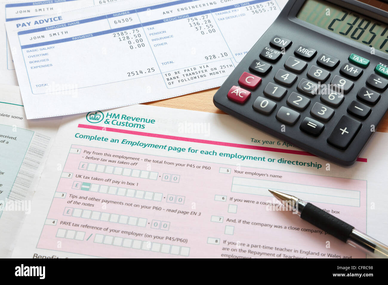 Foto von einem britischen Self-Assessment Steuererklärung mit Taschenrechner und Gehaltsabrechnungen. Stockfoto