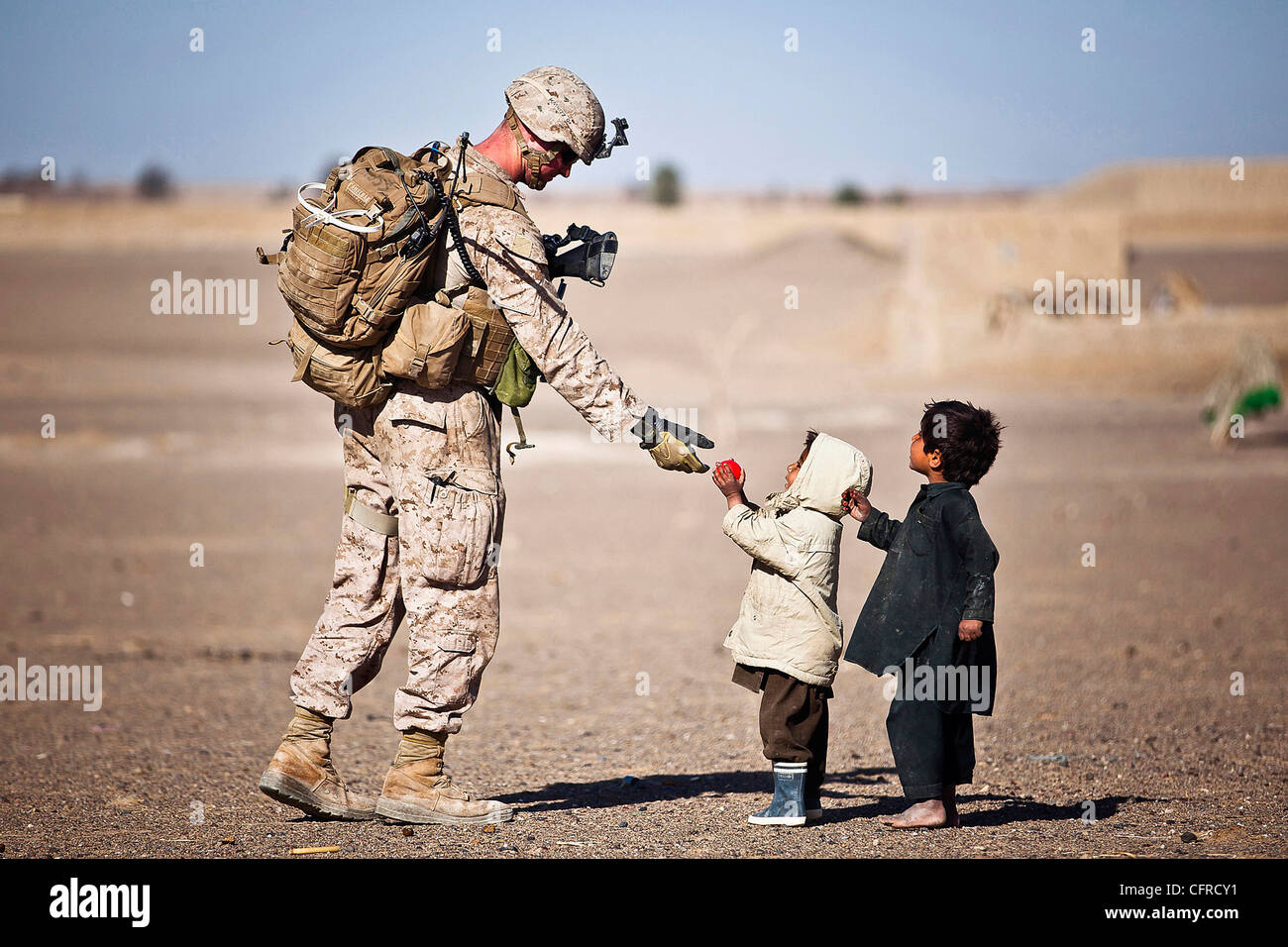 U.S. Marine Lance Cpl. Tom Morton Hände einem afghanischen Kind eine Spielzeug während einer Sicherheitspatrouille 25. Februar 2012 in Safar Basar, Afghanistan. Stockfoto