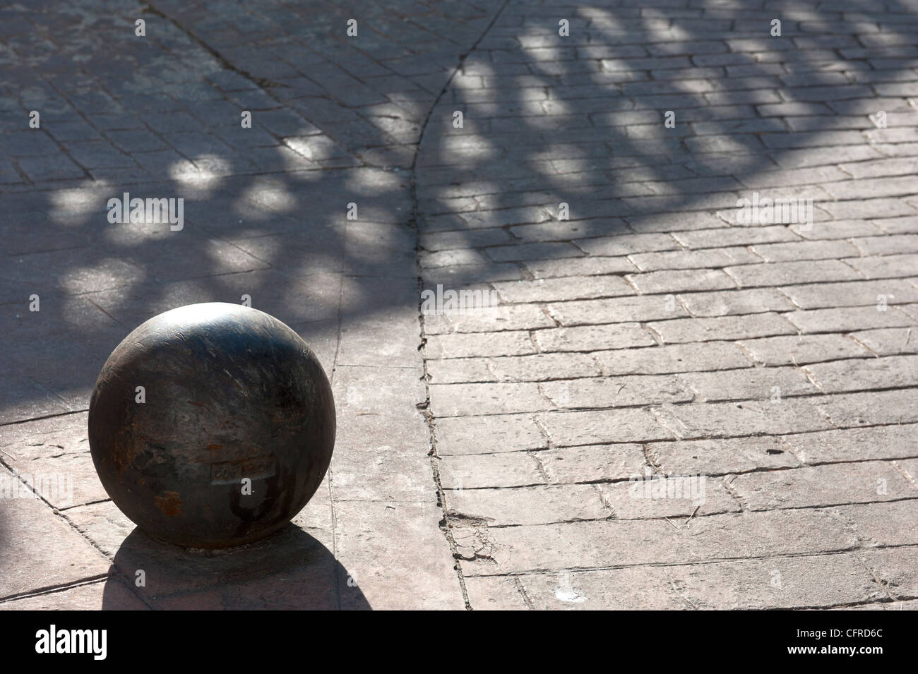 Stein Kugel auf Pflastersteine mit Schatten Muster der angrenzenden Zaun Stockfoto