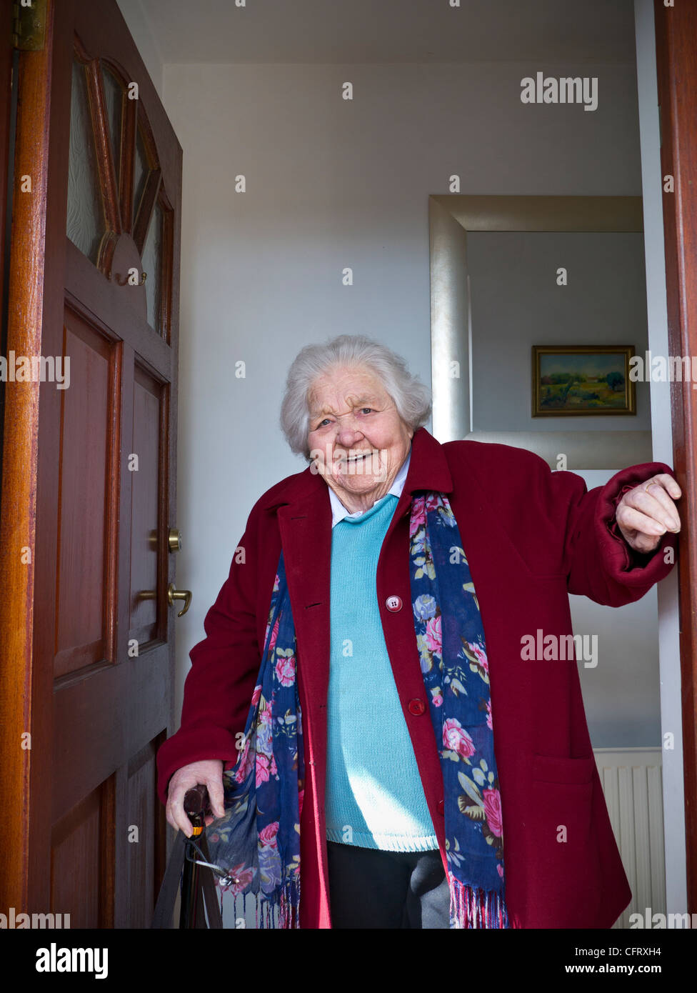 Happy 98 Jahre älteren Hause besitzende Dame stehend mit Gehstock vor ihr offene Haustür bereit für einen Tagesausflug Stockfoto