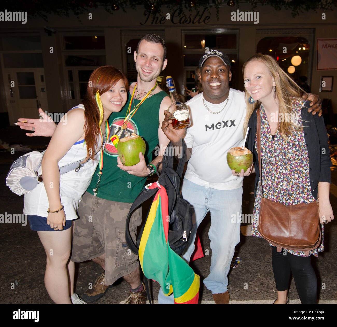 Nachtschwärmer mit Kokosnuss Getränke und Schnaps Flasche Notting Hill Karneval Straße bei Nacht-London-Uk Stockfoto
