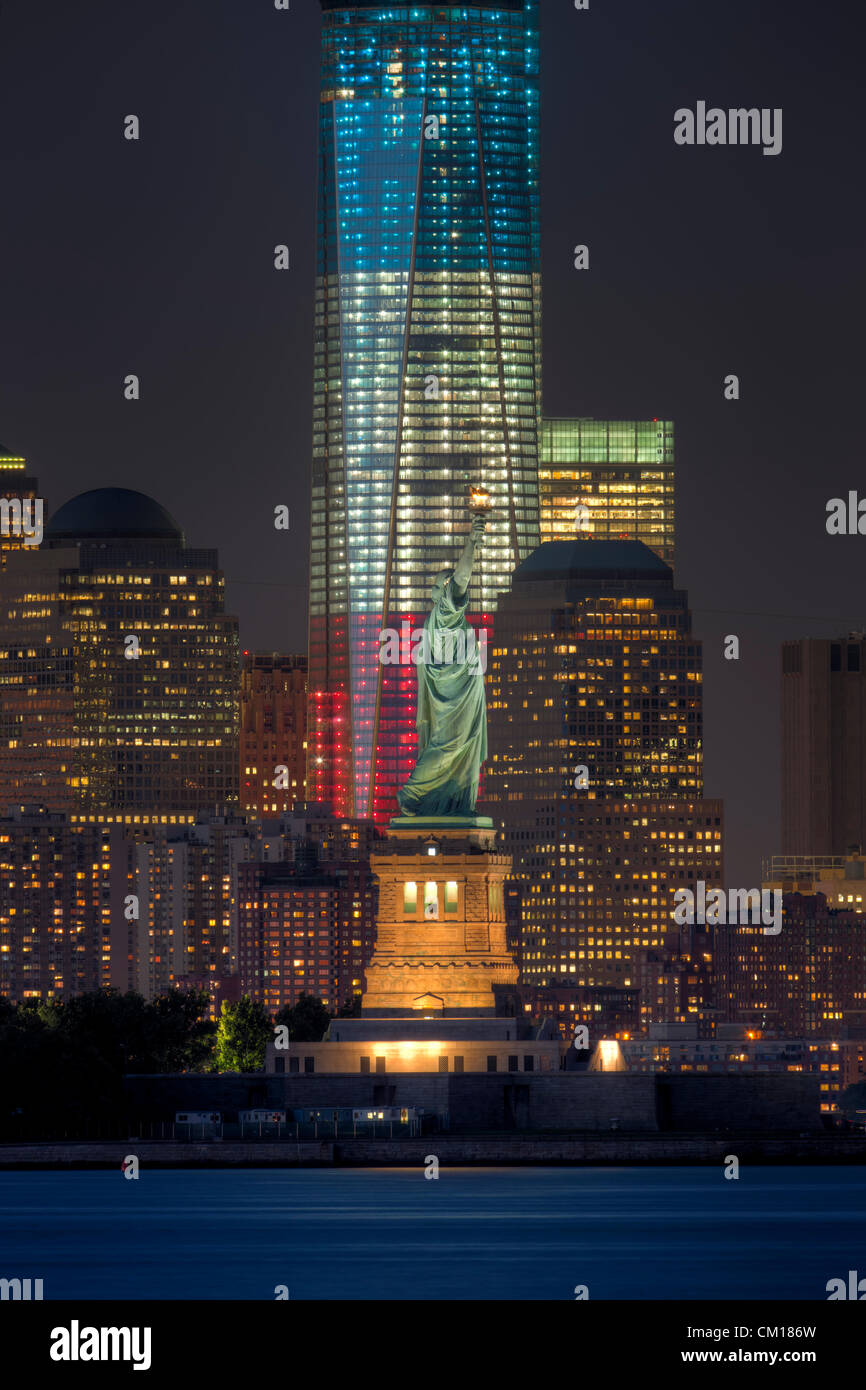 Zwei Symbole der Freiheit, der Freiheitsstatue und der Freedom Tower in rot, weiß und blau leuchtet, leuchtet in der Dämmerung in New York City. Stockfoto