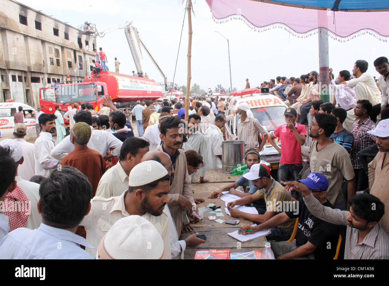 Angehörige von den verbrannten Arbeiter überprüfen die Namenslisten in einem Camp außerhalb der Fabrik in Karatschi 12. September 2012. Atleast 289 Arbeiter wurden verbrannt, wenn Feuer eine Textilfabrik in Karachi verschlungen. Stockfoto