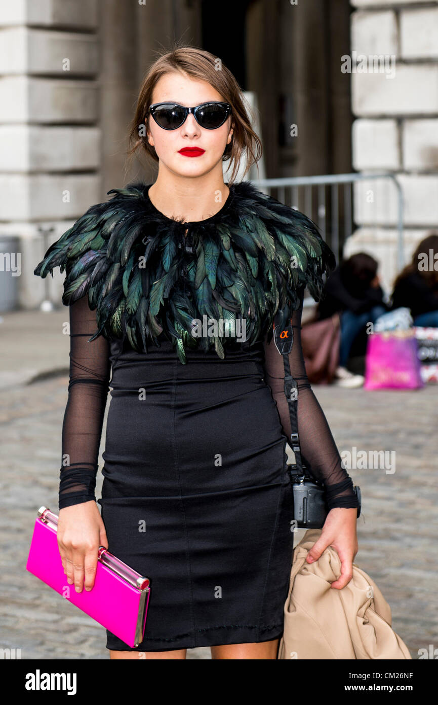 17. September 2012, UK. London Fashionweek im Somerset House, London. Die berühmte und modische besuchen die Shows oder rein zu hängen im Innenhof. Frau im schwarzen Kleid mit Federn und rosa Clutch. Stockfoto