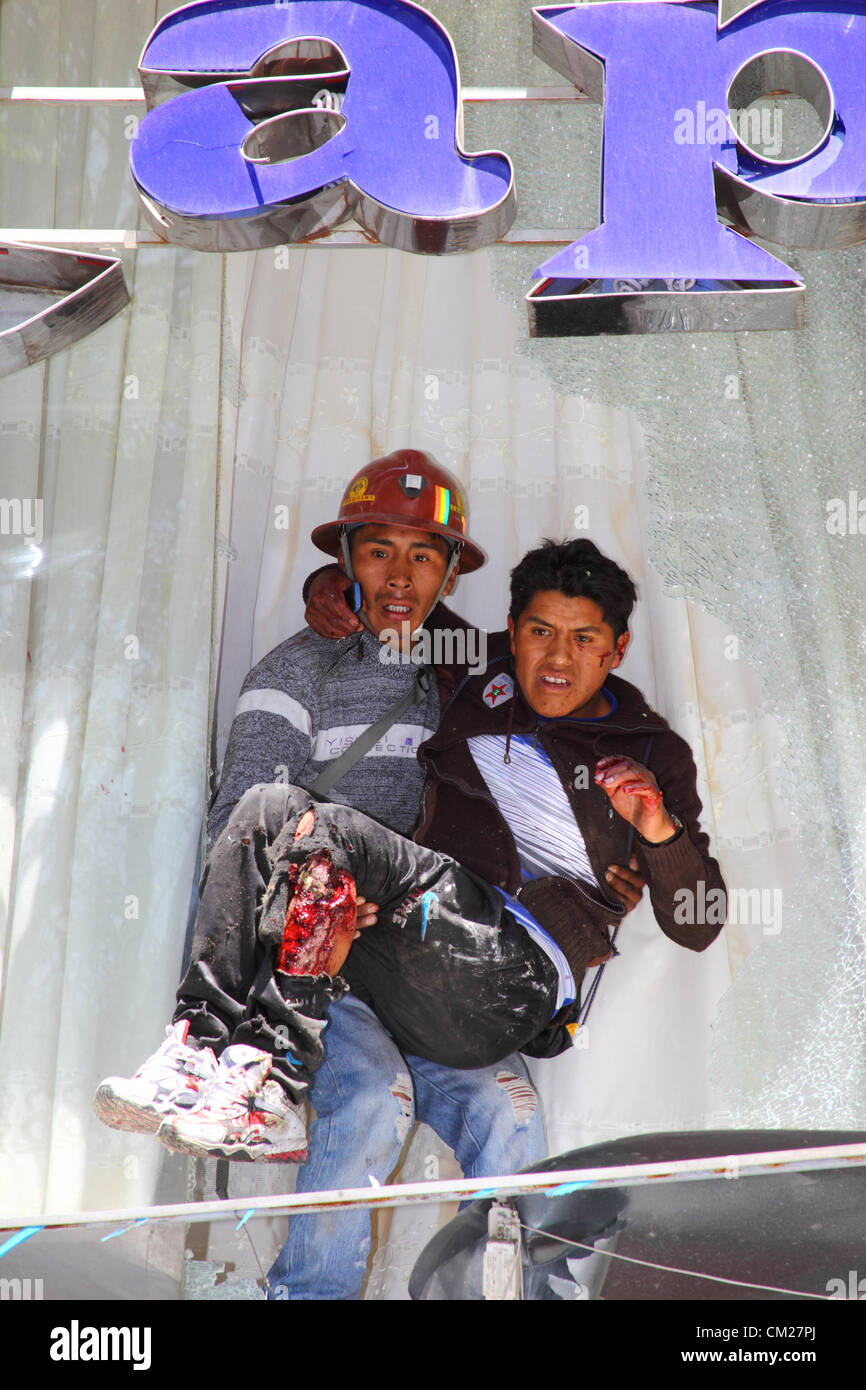 LA PAZ, BOLIVIEN, 18. September 2012. Ein verwundeter Bergarbeiter, der für den staatlichen Bergbaukonzern COMIBOL arbeitet, wird von einem Kollegen aus dem Gebäude evakuiert, in dem sich die Büros der FSTMB befinden. Das Gebäude wurde von kooperativen Bergleuten während eines marsches mit Steinen und Dynamit angegriffen, um einen größeren Anteil der Konzession für die Colquiri-Mine bei Oruro zu fordern. Kooperative und staatlich angestellte Bergleute streiten seit mehreren Wochen über die Kontrolle der Mine, wobei die Proteste in der letzten Woche eskalierten. Stockfoto