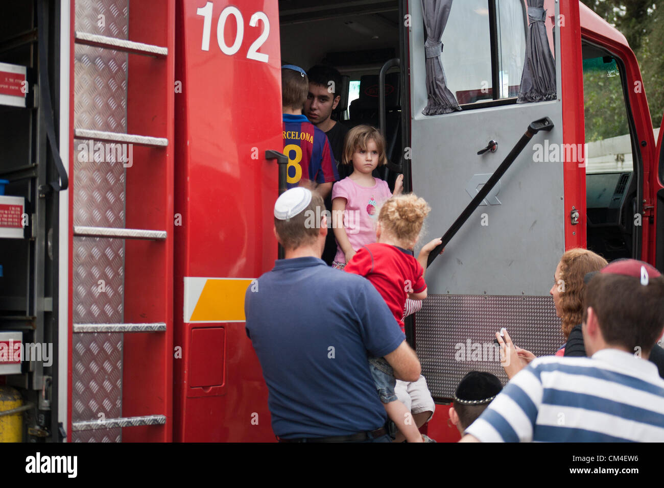 Jerusalem, Israel. 2. Oktober 2012. Kinder genießen die Möglichkeit, Feuerwehrautos einsteigen und sehen Feuerlöschgeräte aus der Nähe an der Givat Mordechai Station wie Jerusalem Feuerwehr seine Türen für die Öffentlichkeit öffnet.  Jerusalem, Israel. 2. Oktober 2012.  Jerusalem-Feuerwehr öffnet seine Türen für die Öffentlichkeit in Givat Mordechai Station ermöglicht der Öffentlichkeit, die Arbeit der Feuerwehrleute aus nächster Nähe zu sehen. Die Jerusalem-Feuerwehr entspricht jährlich mehr als 8.000 Veranstaltungen. Stockfoto