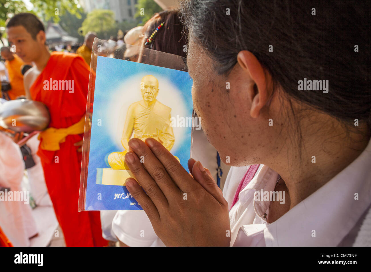 20. Oktober 2012 - Bangkok, Thailand - eine Frau hält eine buddhistischen Gebet Karte und neigt ihren Kopf in Gebet und Respekt, wie buddhistische Mönche ihr bei einem speziellen Almosen Zeremonie in Bangkok passieren. Mehr als 2.600 buddhistische Mönche aus über Bangkok und Tausende Gläubige Thai Buddhisten besuchte die Masse Almosen Zeremonie im Benjasiri Park in Bangkok Samstagmorgen. Die Zeremonie war, Lebensmittel und Geldspenden für buddhistische Tempel in Thailand Gewalt erhöhen südliche Provinzen geplagt. Aufgrund einer laufenden langen laufen Aufstand von muslimischen Separatisten viele buddhistische Mönche in Pattani, Narathiwat und Y Stockfoto