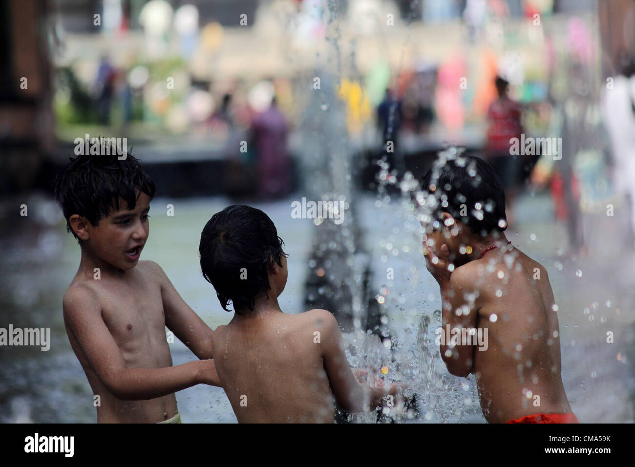 Kashmiri muslimische Kinder spielen mit Brunnen während heißer Tag in Srinagar, der Sommer-Capiatl des indischen Kaschmir auf 1,7,2012 Foto/Altaf Zargar/Zuma Press Stockfoto