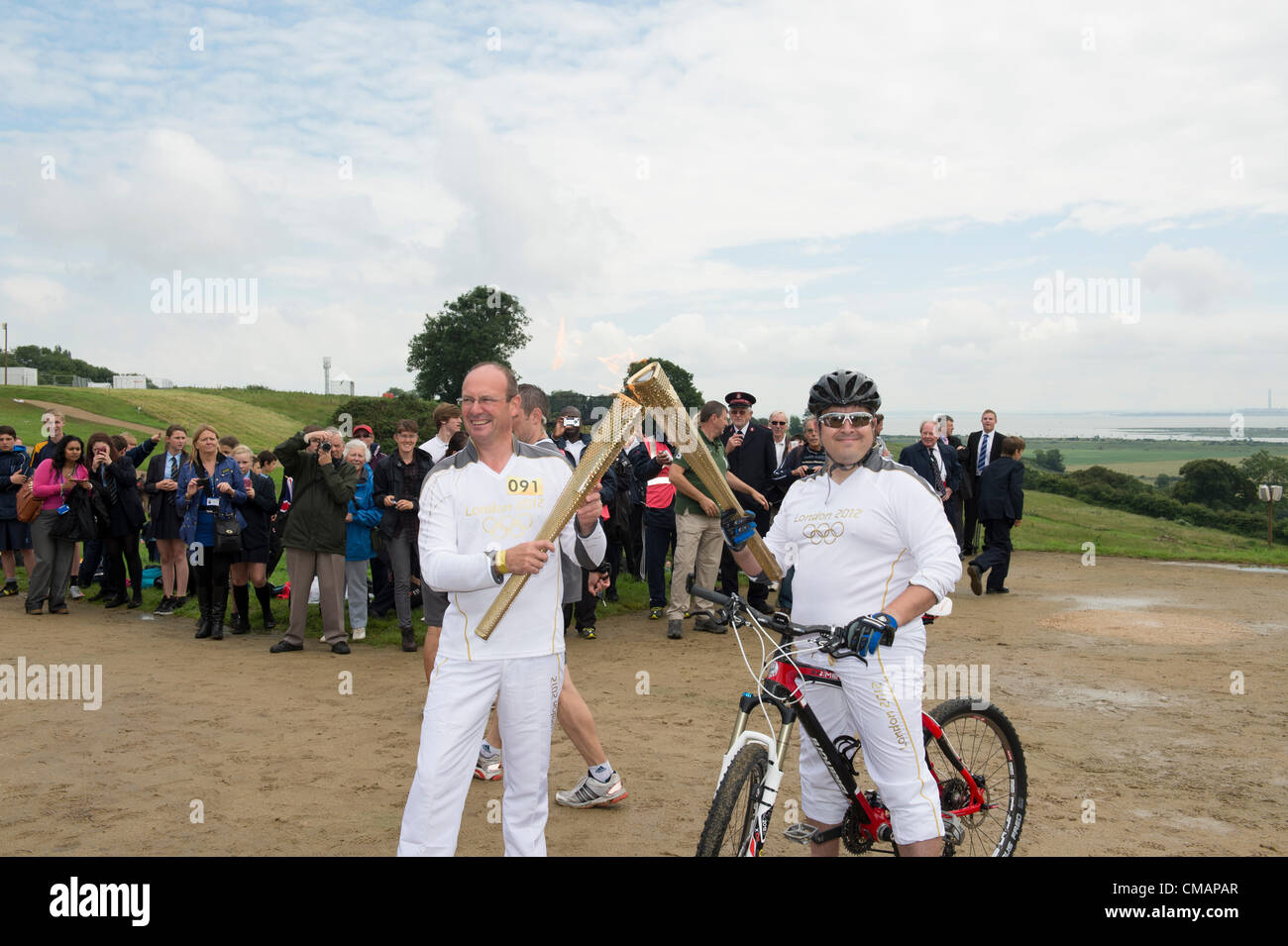 6. Juli 2012, Hadleigh Farm, Essex, England. Die Olympische Fackel durchläuft der Olympischen Mountainbike Ort wo Dan Jarvis (L) die Fackel um einen Abschnitt des Rennens nimmt route vor der Übergabe an Läufer Kim Axford (nicht abgebildet) und ab in Richtung Basildon und Grautöne. Das Wetter wurde zu trocken und sonnig, wie die Fackel am Veranstaltungsort angekommen. Stockfoto