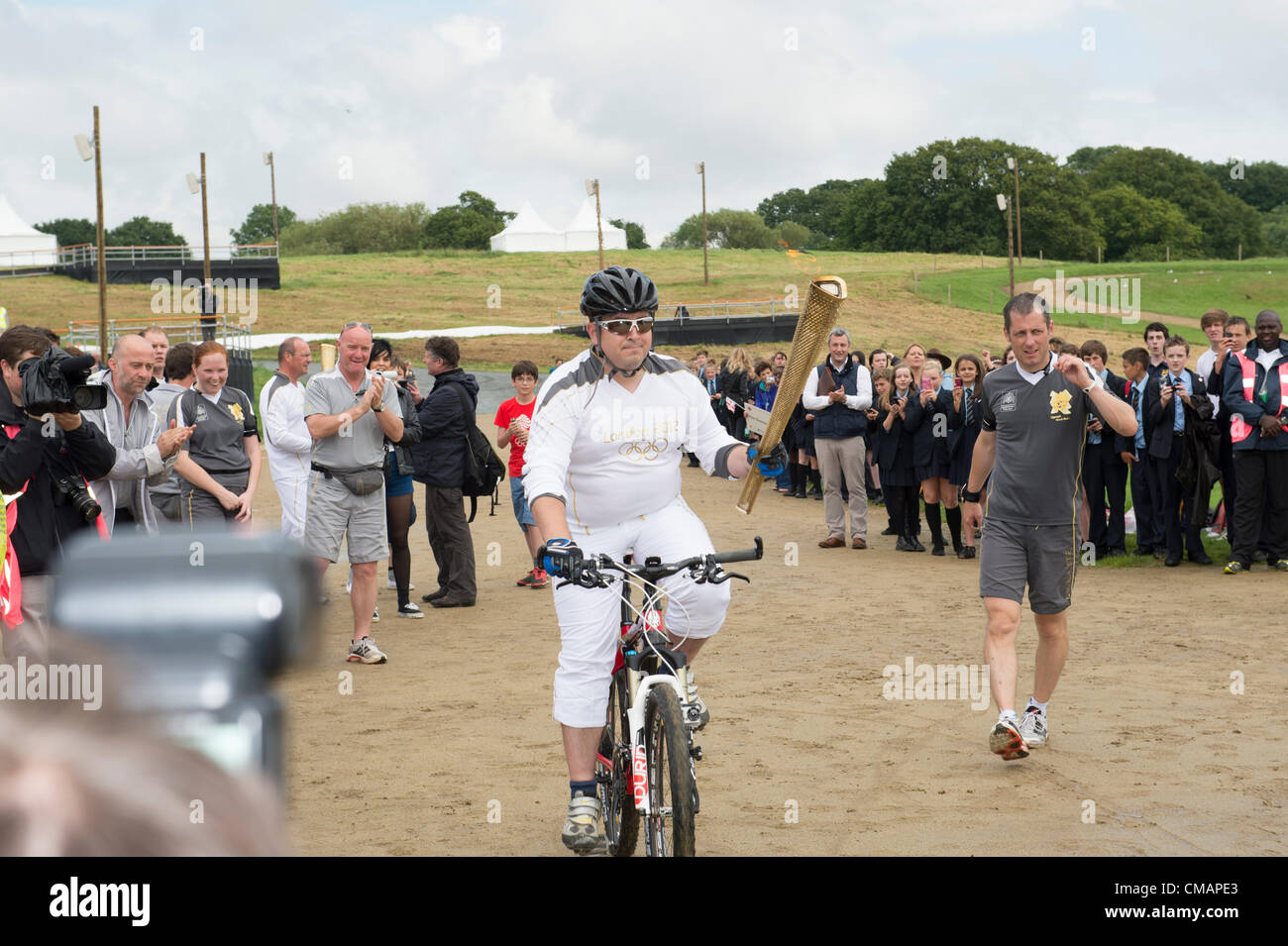 6. Juli 2012, Hadleigh Farm, Essex. Die Olympische Fackel durchläuft der Olympischen Mountainbike Ort wo Dan Jarvis die Fackel um einen Abschnitt des Rennens nimmt vor Übergabe an Läufer Kim Axford route und ab in Richtung Basildon und Grautöne. Das Wetter wurde zu trocken und sonnig, wie die Fackel an der Abendkasse gegen den neuesten Wettertrend nass, nass, nass ankam. Stockfoto