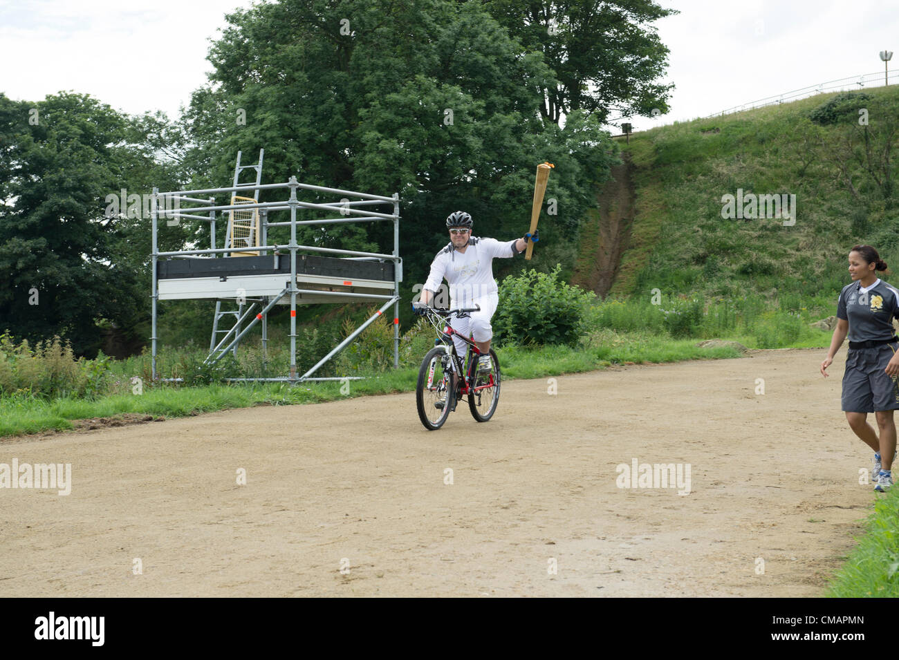 6. Juli 2012, Hadleigh Farm, Essex. Die Olympische Fackel durchläuft der Olympischen Mountainbike Ort wo Dan Jarvis die Fackel um einen Abschnitt des Rennens nimmt vor Übergabe an Läufer Kim Axford route und ab in Richtung Basildon und Grautöne. Das Wetter wurde zu trocken und sonnig, wie die Fackel an der Abendkasse gegen den neuesten Wettertrend nass, nass, nass ankam. Stockfoto