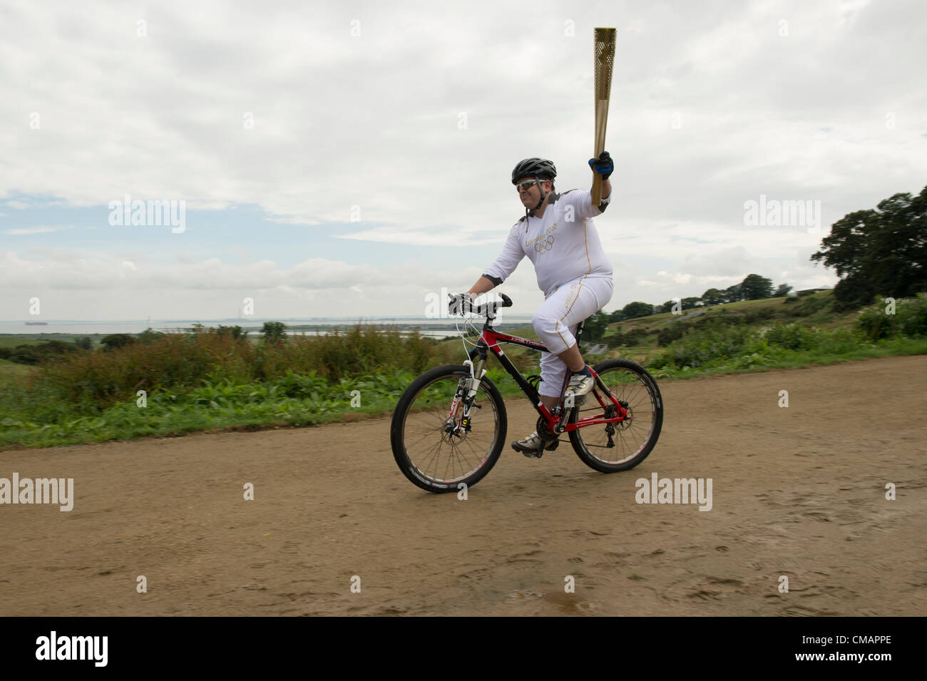 6. Juli 2012, Hadleigh Farm, Essex, England. Die Olympische Fackel durchläuft der Olympischen Mountainbike Ort wo Dan Jarvis die Fackel um einen Abschnitt des Rennens nimmt route vor der Übergabe an Läufer Kim Axford (nicht abgebildet) und ab in Richtung Basildon und Grautöne. Das Wetter wurde zu trocken und sonnig, wie die Fackel am Veranstaltungsort angekommen. Stockfoto