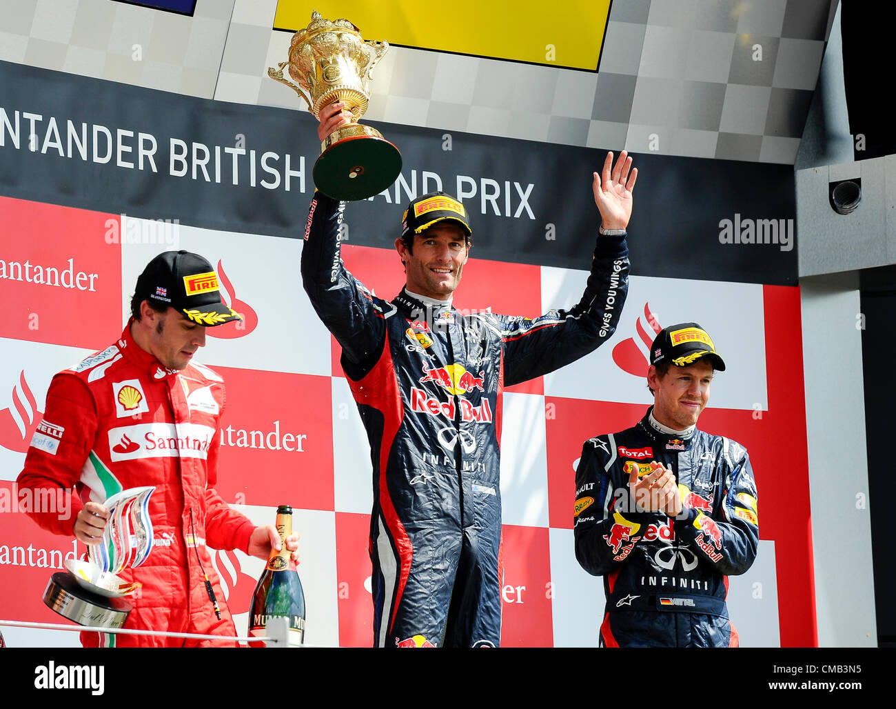 08.07.2012 Towcester, England. Mark Webber aus Australien und Red Bull Racing hebt seine Sieger-Trophäe auf dem Podium nach dem Rennen beim britischen Grand Prix Santander, Runde 9 der 2012 FIA Formel 1 Weltmeisterschaft in Silverstone. Stockfoto