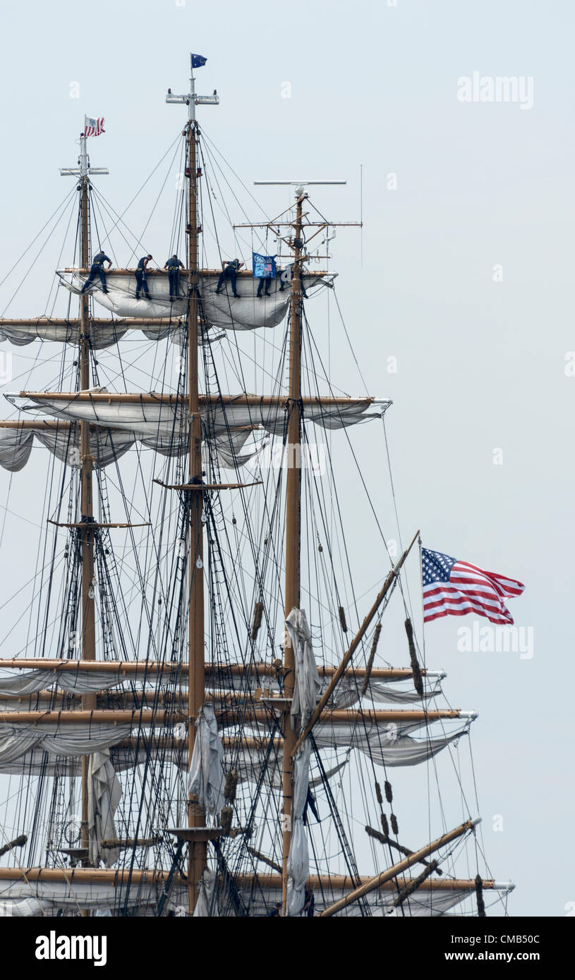 DIE US-Küstenwache rollt die Segel auf Amerikas großem Schiff Eagle, während es an seinem Heimathafen Fort Trumbull, New London, CT, anlegt, wo es im Sommer oft zu sehen ist. Der Eagle ist das einzige Segelschiff im aktiven Dienst des amerikanischen Militärs. Eine amerikanische Flagge fliegt vom Heck. Speicherplatz kopieren. Original Live News Bildunterschrift: New London, Connecticut, USA - 7. Juli 2012: Das Hochschiff Eagle der US-Küstenwache landet während des OpSail 2012 Festivals in Fort Trumbull. Kadetten hoch oben in der Takelage rollten die Segel nach der Parade von Sail während der Feierlichkeiten zum 200. Jahrestag des Krieges von 1812. Stockfoto