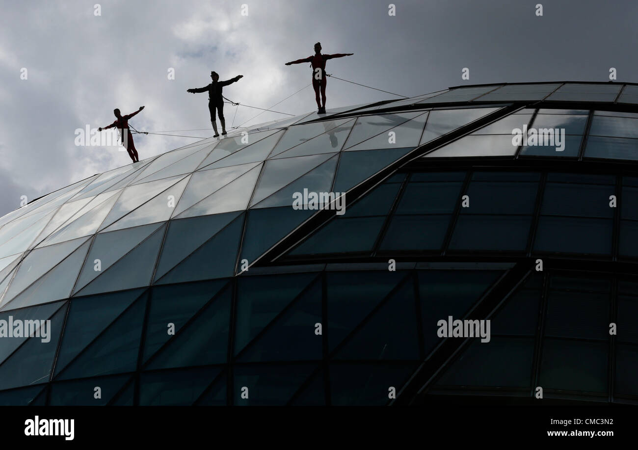 London, England, UK. Sonntag, den 15. Juli 2012. Überraschungen: STREB, Elizabeth Streb, 63, im schwarzen Anzug, führte zwei "Helden" in einem abseilen Quest durch zu Fuß die Fassade des Rathauses, die von Sir Norman Foster erstellt wurde. Mit dem Aufzug, der London International Festival des Theaters inszeniert, und der Bürgermeister von London und der London Festival 2012, Überraschungen unterstützt: Streb ist ein Ereignis der Olympischen Spiele 2012 in London feiern. Stockfoto