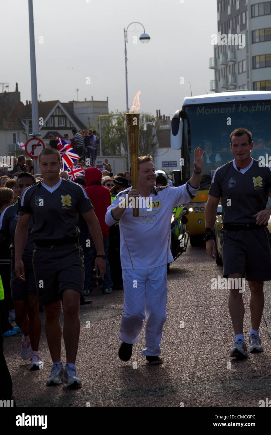 Komiker Eddie Izzard trägt das Olympische Feuer in Bexhill am Meer, UK am 17. Juli 2012 während des Olympischen Fackellaufs. Das Relais wurde seine Fortschritte durch East Sussex und West Kent Stockfoto