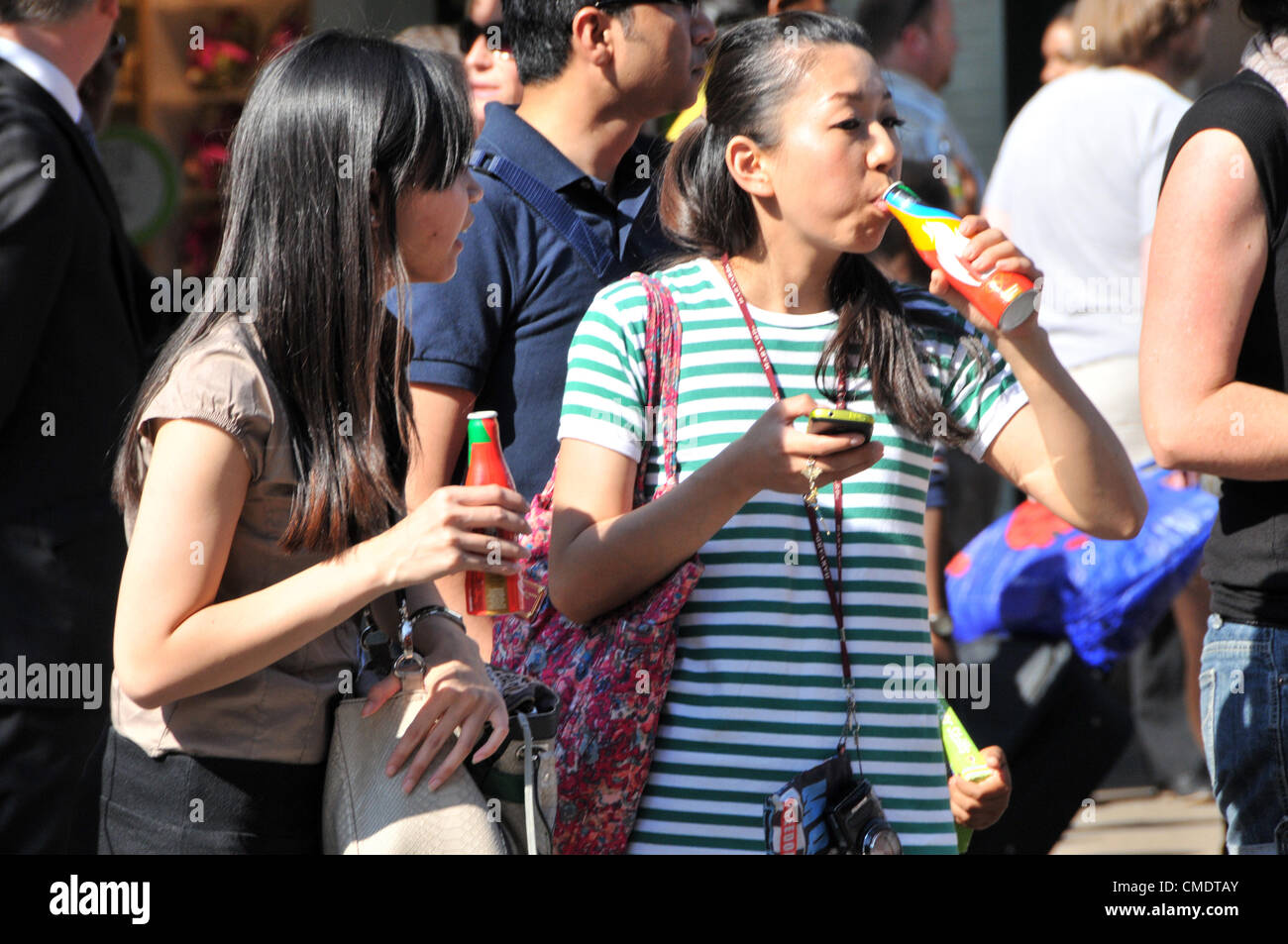 Oxford Street, London, UK. 26. Juli 2012. Mitglieder der Menge trinken kostenlose Flaschen Coca Cola Spiele Sponsor, als des Olympischen Fackellaufs verläuft entlang der Oxford Street im Zentrum von London und nähert sich das Ende seiner 8.000 Meile Reise in ganz Großbritannien. Stockfoto