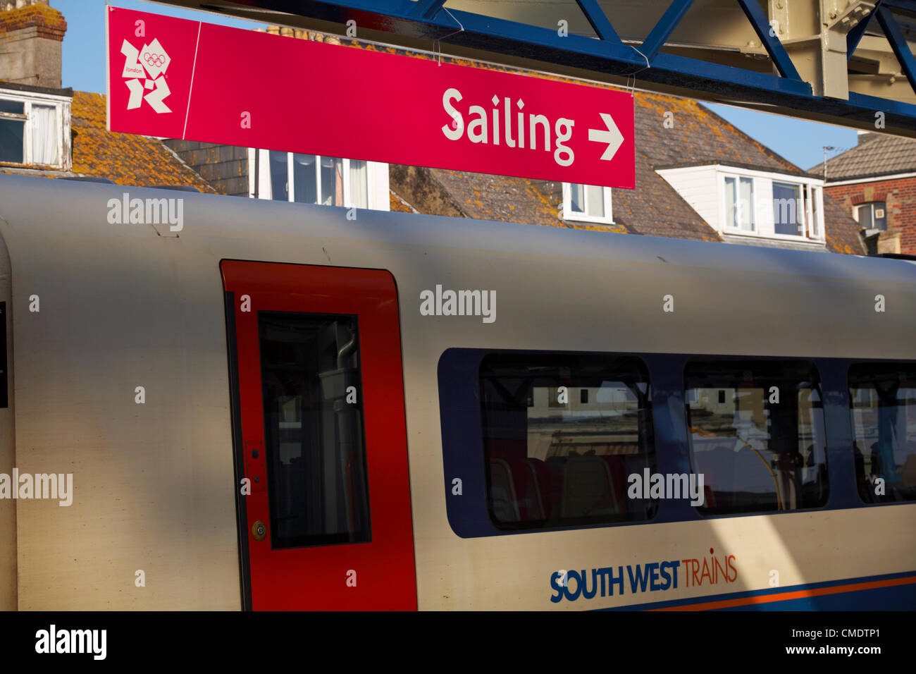 Weymouth, Großbritannien Mittwoch, 25. Juli 2012. Letzte Vorbereitungen für die Olympischen Spiele in Weymouth, Großbritannien. Olympischen Spiele Segeln Schild mit Pfeil am Bahnhof Weymouth mit Süd-West Zug am Bahnsteig - South West Trains wird voraussichtlich über die Olympischen Spiele, die die Passagiere von und nach Weymouth beschäftigt sein Stockfoto