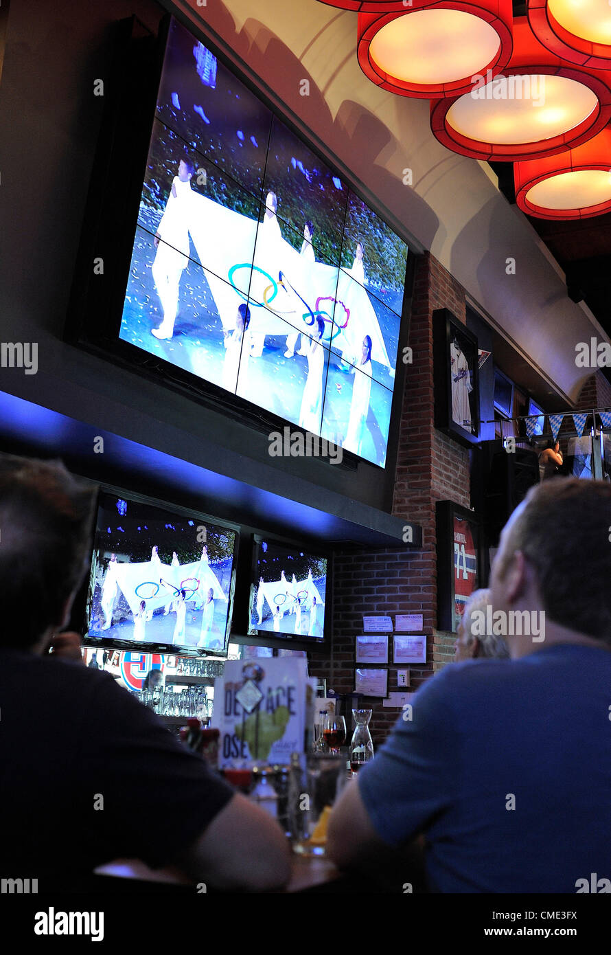 Manche Menschen sehen Spiele 2012 in London Olympischen Eröffnungsfeier im Fernsehen, voraussichtlich von einem weltweiten Publikum von mehr als 1 Milliarde Menschen, fotografiert in einem Cage Aux Sportbar am 27. Juli 2012 in Montreal, Kanada live verfolgt werden. Stockfoto