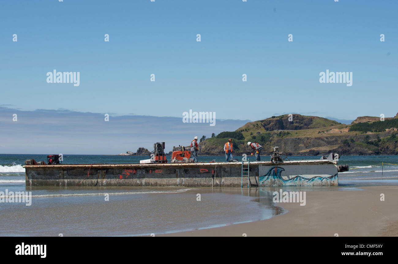 1. August 2012 - Newport, Oregon, US - Arbeiter benutzen einen großen Kran und eine Diamant Kanten schneiden sah eine massive gestrandet schneiden dock in Stücke auf Agate Beach in der Nähe von Newport.  Die riesigen japanischen Dock wurde vom letztjährigen Tsunami weggerissen und vor fast zwei Monaten an einer Oregon Strand gespült. Der japanischen Tsunami riss das Dock im März 2011 Lose aus ihrer Verankerung in der nördlichen japanischen Misawa. Eine 15-Monats-Odyssee über den Pazifik endete am 5. Juni bei einer Flut. (Bild Kredit: Robin Loznak/ZUMAPRESS.com ©) Stockfoto