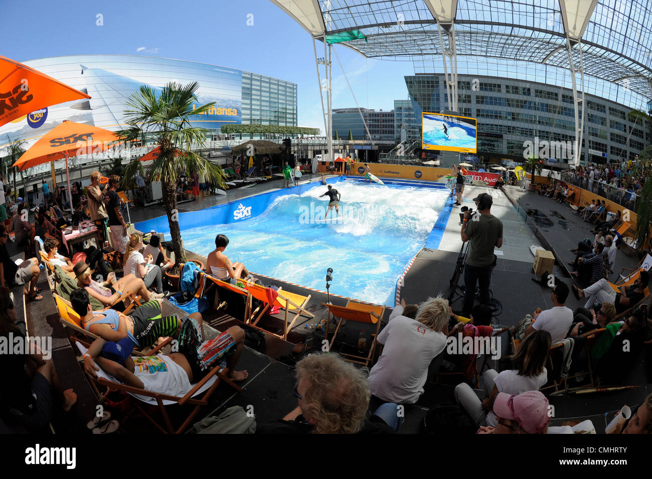 12. August 2012. Surfer und Publikum bei der Surf & Style, stationäre Welle reiten em. Die Veranstaltung fand statt am Flughafen München mit "The Wave", die größte künstliche Welle und 80 Surfer, Samstag und Sonntag, 11, 12 August 2012. Stockfoto