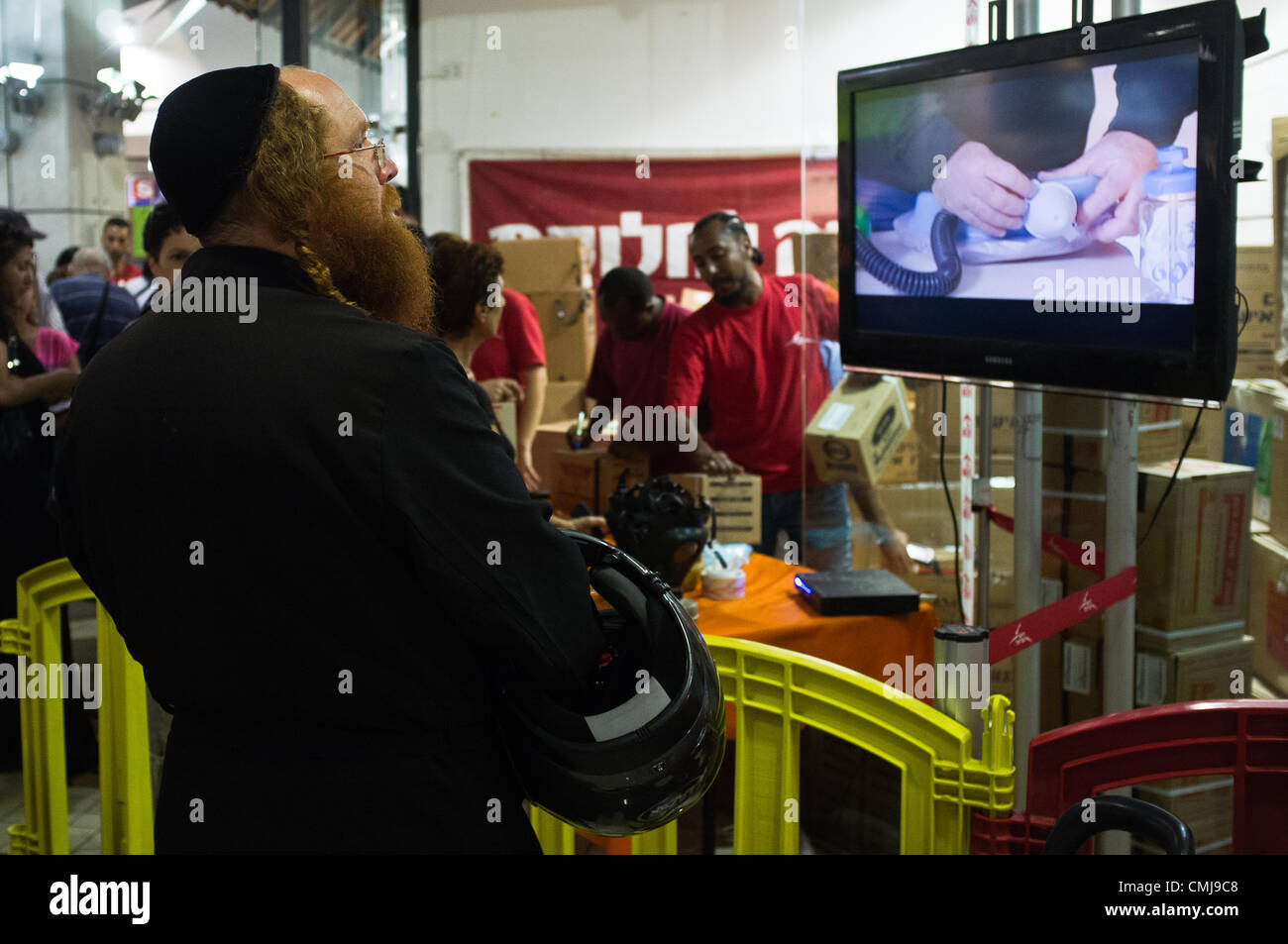 15. August 2012. Ein Ultra-orthodoxer Haredi Mann Uhren eine Demo-Video, wie er in der Schlange vor einer Gasmaske Verteilungspunkt in Hadar Einkaufszentrum wartet. Jerusalem, Israel. 15. August 2012.  Zivilisten strömen Gasmaske Verteilungspunkt als Erneuerung der veralteten chemischen/biologischen Kriegsführung Verteidigung Kits Heimatfront Befehl fordert. Antwort in Jerusalem steigt mit überwältigender Mehrheit wegen in Jerusalem-Teheran Kriegsrhetorik erhöht. Stockfoto