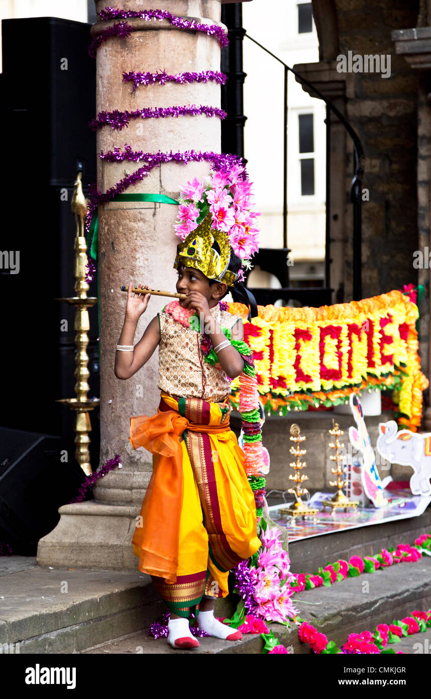 Ein kleiner Junge beim Flötenspiel gekleidet in indische Tracht auf dem Diwali Festival 2. November 2013 an der Guildhall, Domplatz, Peterborough, England Stockfoto