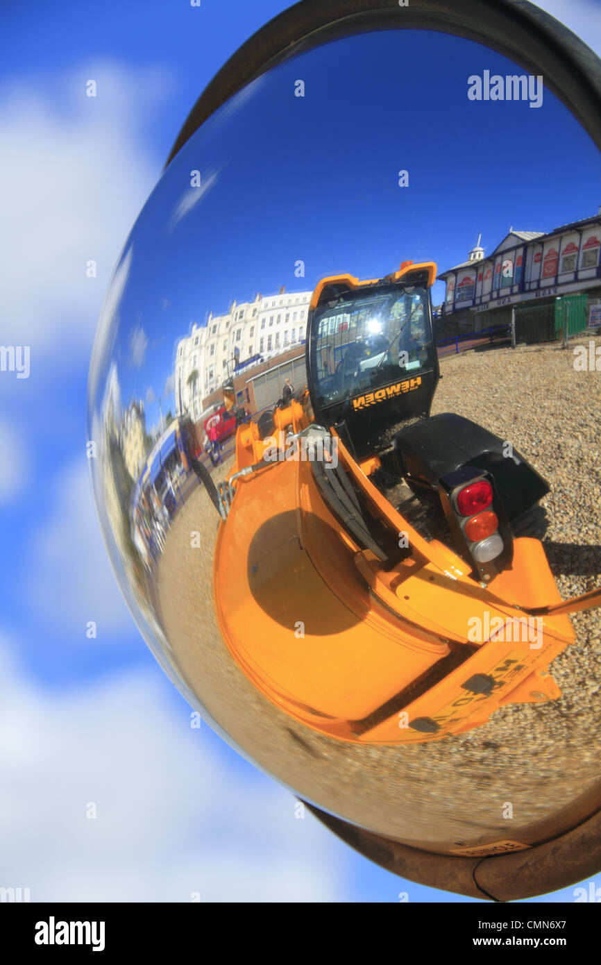 Eine gelbe Bulldozer reflektiert in einem konvexen Spiegel auf Eastbourne Strand, East Sussex, England Stockfoto